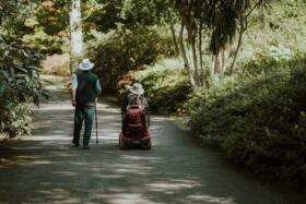 Two people enjoying the outdoors, one using a walking stick and the other using a wheelchair