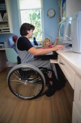 Female wheelchair user with children using a computer