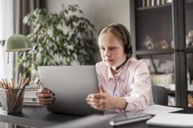 A girl wearing a headset and looking at a laptop