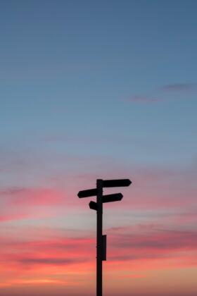 A sign post with an evening sky in the background