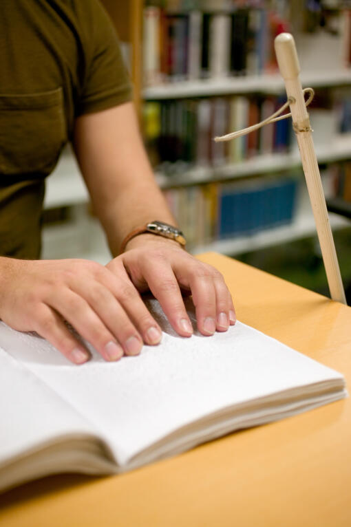 Person at a library with a walking cane resting against the table